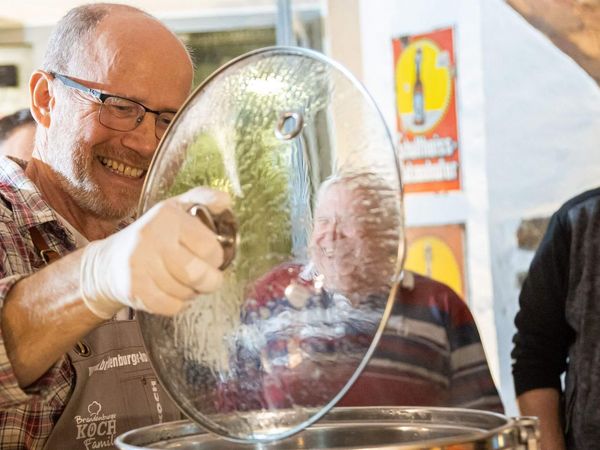 Fürstenwalder Braufreund Bernd zeigt während eines Braukurses den Teilnehmenden den Inhalt eines Topfes.