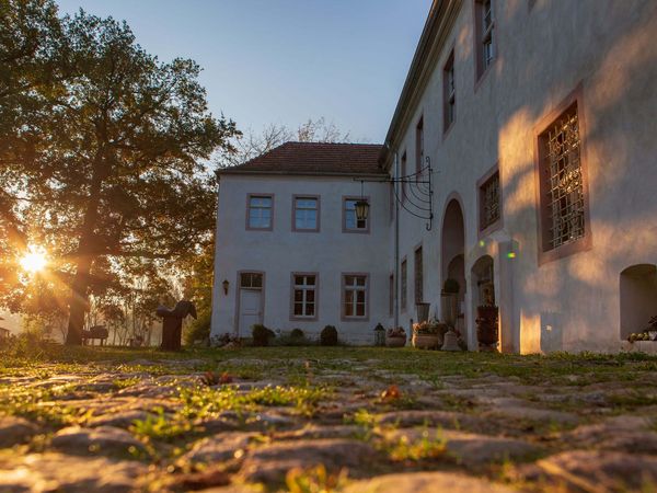 Innenhof Schloss Neuenhagen mit Sonne hinter den Bäumen 