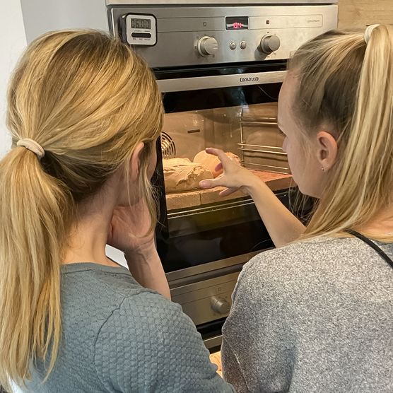 Zwei Frauen schauen auf das Brot im Ofen