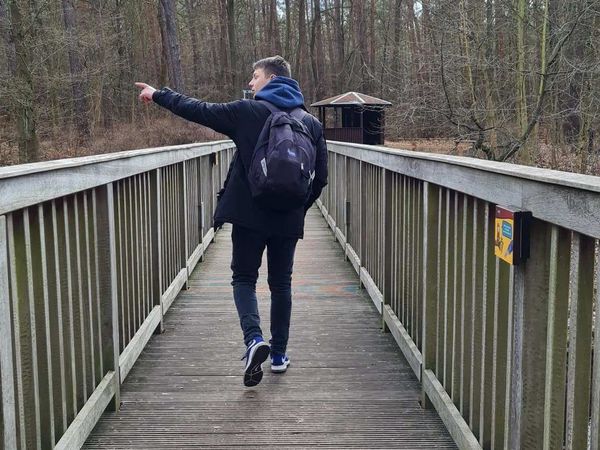 Ein Wanderer läuft über eine alte Holzbrücke im Löcknitztal