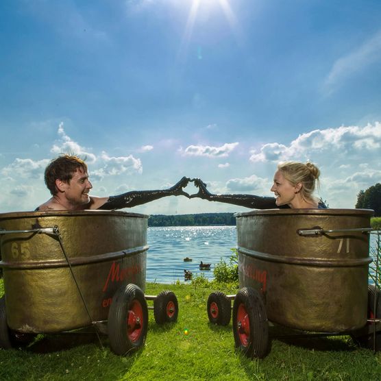 Ein Pärchen liegt in Moor-Wannen und blickt auf den Scharmützelsee