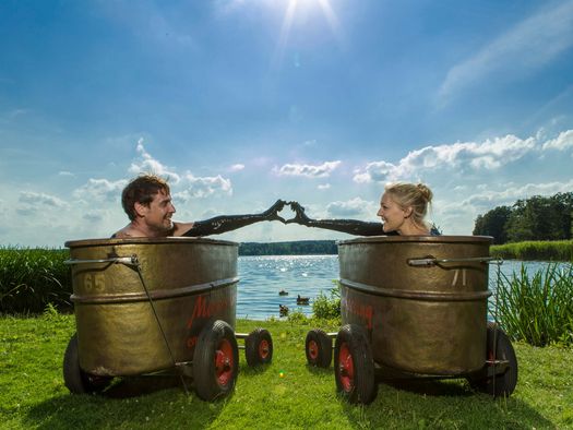 Ein Pärchen liegt in Moor-Wannen und blickt auf den Scharmützelsee