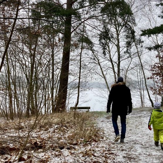 Ein Vater spaziert mit seinem Kind entlang eines zugefrorenen Sees