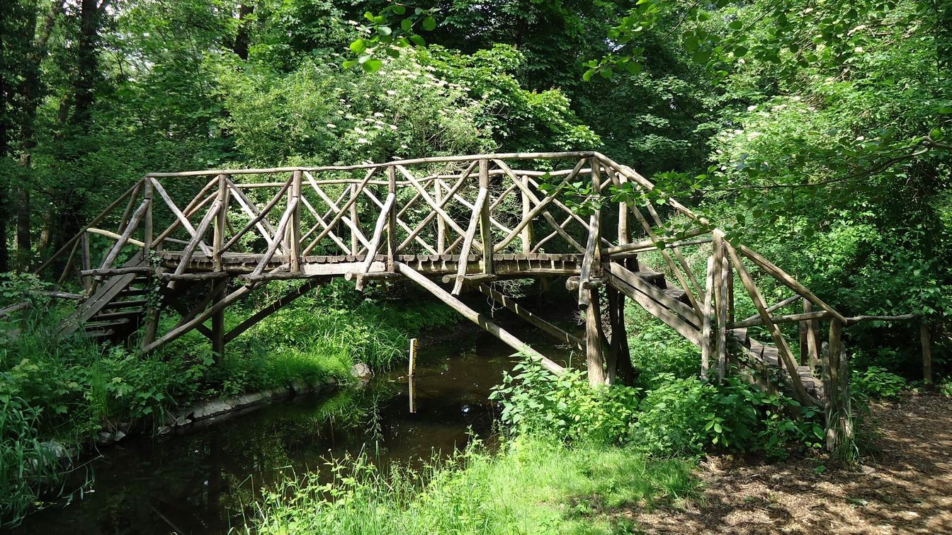 Eine hölzerne Brücke führt über einen idyllischen Fließ im kleinen Spreewald Park in der Gemeinde Schöneiche bei Berlin