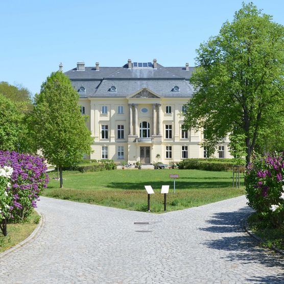 Vorderansicht Schloss Trebnitz mit Blumen und Bäumen 