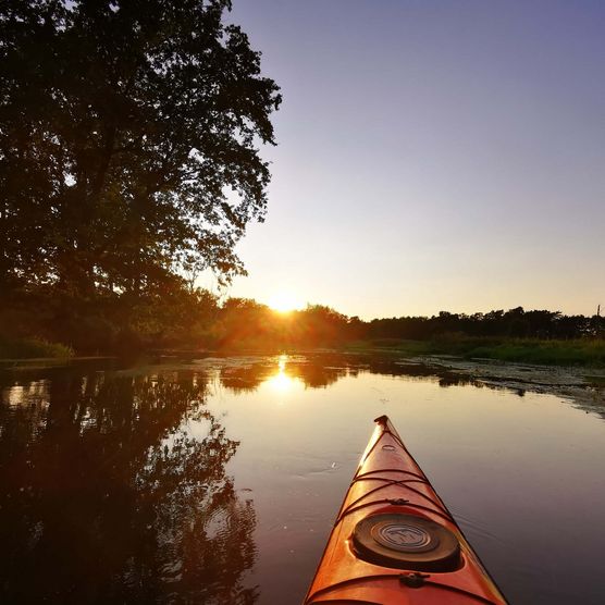 Kajak gleitet auf dem Wasser bei Sonnenuntergang 