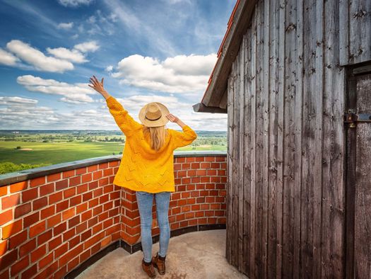 Eine Frau steht auf dem Bismarckturm in Bad Freienwalde und genießt die Aussicht auf die Weite des Oderbruchs
