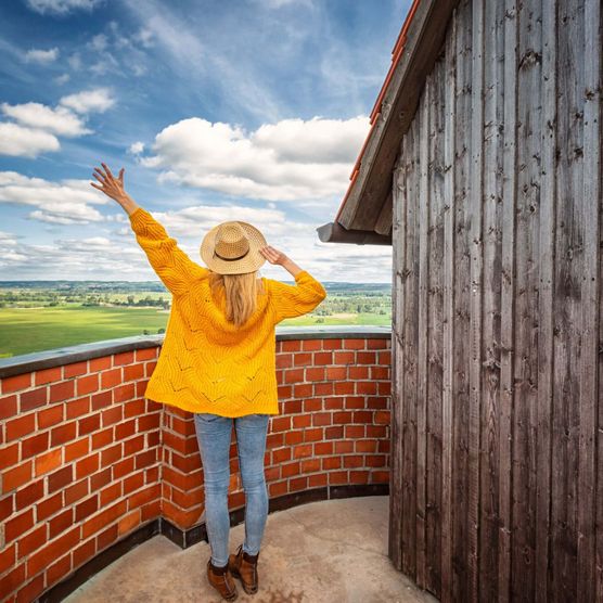 Eine Frau steht auf dem Bismarckturm in Bad Freienwalde und genießt die Aussicht auf die Weite des Oderbruchs