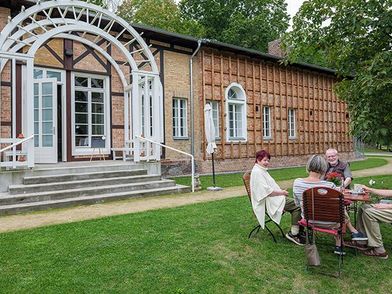 4 Personen sitzen gemütlich vor dem Schweizer Haus in Seelow