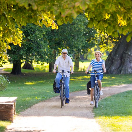 Zwei Menschen radeln durch den Schlosspark Neuhardenberg