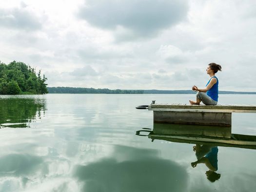 Eine Frau macht Yoga auf einem Steg am Scharmützelsee