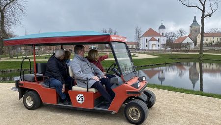 Vier Personen sitzen im Golfcar und schauen sich das Schlossgut an