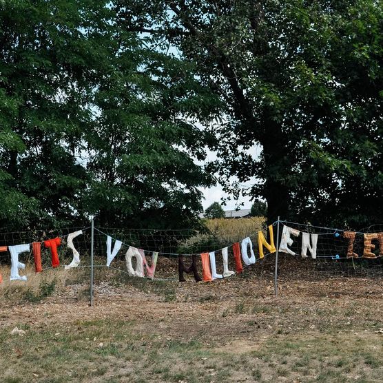 Banner mit Festivalname "Jenseits von Millionen" am Wegesrand 